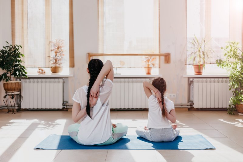 A mom and daughter do yoga together in their home gym while looking out the window (Photo by Mkorobsky - stock.adobe.com)